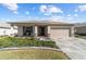 Single-story home featuring a well-manicured lawn, a large driveway, and a two-car garage at 8719 Sw 76Th Street Rd, Ocala, FL 34481