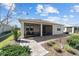 Rear exterior with screened-in patio surrounded by manicured landscaping and lawn at 8719 Sw 76Th Street Rd, Ocala, FL 34481