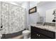 This bathroom has a granite countertop, dark vanity, a shower with a floral curtain, and decorative artwork at 8861 Sw 63Rd Ct, Ocala, FL 34476