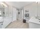 Bright bathroom with double vanity, white cabinets, neutral walls, and a gray decorative stool at 8864 Sw 85Th Loop, Ocala, FL 34481