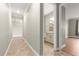 Hallway view showcases tile flooring leading to a bathroom with a granite vanity and a bedroom with modern hardwood floors at 9085 Sw 89Th Loop, Ocala, FL 34481