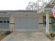 Garage featuring a gray door, the house number, and a manicured yard and blue rocking chair at 9652 Sw 84Th Ter # C, Ocala, FL 34481