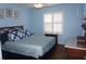 Bedroom featuring hardwood floors, blue walls, and a window with white shutter-style blinds at 11091 Sw 73Rd Ct, Ocala, FL 34476