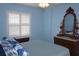 Bedroom featuring blue walls, a ceiling fan, and a window with white shutter-style blinds at 11091 Sw 73Rd Ct, Ocala, FL 34476