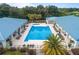 Aerial image of the sparkling community pool with lounge chairs, tables, and tropical landscaping, and metal roofs at 11091 Sw 73Rd Ct, Ocala, FL 34476