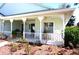 Charming front porch with white railings, ceiling fans, and views of the beautifully landscaped garden at 11091 Sw 73Rd Ct, Ocala, FL 34476