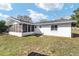 Back exterior view featuring a screened lanai and well-maintained yard with mature trees at 165 Ne 43Rd Ave, Ocala, FL 34470