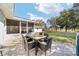 A patio with a brown brick base, a dining table and chairs, a screened-in room, and a big backyard with trees at 165 Ne 43Rd Ave, Ocala, FL 34470