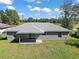 Rear view of a home with a grassy backyard and a covered concrete patio at 206 Emerald Rd, Ocala, FL 34472