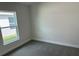This is a bedroom with neutral walls, gray carpet, base trim, and a window on the left side at 2150 Nw 23Rd Loop, Ocala, FL 34475
