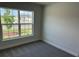 This is a bedroom with neutral walls, gray carpet, base trim, and a window overlooking the front yard at 2150 Nw 23Rd Loop, Ocala, FL 34475