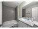 Well-lit bathroom with a shower-tub combo, gray tiled walls, and a large vanity with sink at 22242 Sw Marine Blvd, Dunnellon, FL 34431