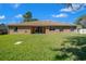 Large backyard with green lawn and mature trees, features sliding glass doors leading into the home at 2301 Se 24Th Ave, Ocala, FL 34471