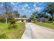 Inviting single-story home with a long driveway and a screened-in patio, surrounded by mature trees and lush landscaping at 3301 Se 32Nd Ave, Ocala, FL 34471