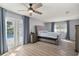 Bright main bedroom featuring French doors to the pool, ceiling fan, and tufted headboard at 3301 Se 32Nd Ave, Ocala, FL 34471