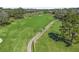 Aerial view of a golf course with cart path, lush greenery, and mature trees on a sunny day at 3848 Nw 85Th Ter, Ocala, FL 34482