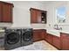 Modern laundry room equipped with front-loading washer and dryer, custom cabinetry, countertop and sink at 3848 Nw 85Th Ter, Ocala, FL 34482