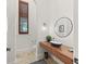 Modern powder room featuring a floating wood vanity with vessel sink, round mirror, designer lighting and a window with shutters at 3848 Nw 85Th Ter, Ocala, FL 34482