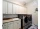 Modern laundry room with stainless steel washer and dryer, sink, and storage cabinets at 4103 Se 10Th Ave, Ocala, FL 34480