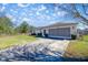 Exterior angle of single story home showing garage, nice green bushes, and driveway at 4858 Sw 143Rd Loop, Ocala, FL 34473