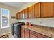 Well-lit laundry room with wood cabinets, granite countertops, and modern washer and dryer at 5417 Sw 49Th Ave, Ocala, FL 34474