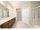 Bathroom with double sink vanity, framed mirror, tiled floor, and glass-enclosed walk-in shower at 6780 Sw 91St Cir, Ocala, FL 34481