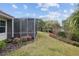 Backyard featuring lawn and mature gardens adjacent to a screened in patio on a sunny day at 8223 Sw 113Th Ln, Ocala, FL 34481