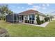 Exterior shot of the back of a property featuring a screened patio, lawn, and garden at 8223 Sw 113Th Ln, Ocala, FL 34481