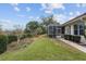 A manicured backyard features a long row of mature flower gardens adjacent to a screened patio at 8223 Sw 113Th Ln, Ocala, FL 34481