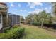 Well-manicured backyard featuring a lawn, sculpted hedge row, and large screened patio on a sunny day at 8223 Sw 113Th Ln, Ocala, FL 34481