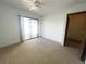 A bright bedroom featuring a ceiling fan, patterned carpet, and sliding glass doors to a patio at 11001 Se Sunset Harbor Rd # A08, Summerfield, FL 34491