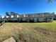 View of condo exterior showing multiple units with balconies and a wide expanse of green lawn at 11001 Se Sunset Harbor Rd # A08, Summerfield, FL 34491