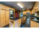 Open kitchen showcasing a center island, wood cabinetry, stainless steel appliances, and dark countertops at 1255 Ne 70Th St, Ocala, FL 34479