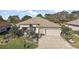 Beige home with a manicured lawn, mature landscaping, and a large concrete driveway at 13424 Se 89Th Terrace Rd, Summerfield, FL 34491