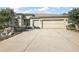 Beige two-car garage home with a well maintained lawn, landscaping, and concrete driveway at 13424 Se 89Th Terrace Rd, Summerfield, FL 34491