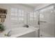 View of the main bathroom featuring a soaking tub, plantation shutters and glass enclosed shower at 13424 Se 89Th Terrace Rd, Summerfield, FL 34491