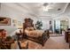 View of the main bedroom showcasing tray ceiling, ceiling fan, access to lanai and ornate wood bed frame at 13424 Se 89Th Terrace Rd, Summerfield, FL 34491