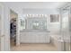 Bathroom with double vanity, granite countertop, tub and glass shower, plus walk-in closet at 13544 Se 89Th Terrace Rd, Summerfield, FL 34491