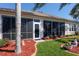 Rear exterior of home featuring screened lanai, manicured lawn and landscaped flower beds at 13544 Se 89Th Terrace Rd, Summerfield, FL 34491
