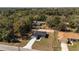 An aerial view shows a home set in a wooded area, surrounded by mature trees and lush greenery at 13568 Se 101St Ter, Belleview, FL 34420