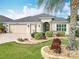 Well-maintained home exterior featuring a three-car garage, a beautiful palm tree, and lush landscaping at 383 Harlow Ln, The Villages, FL 32163