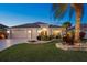 Charming single-story home with a three-car garage, beautiful landscaping and an American flag at 383 Harlow Ln, The Villages, FL 32163