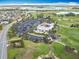 Aerial view of a golf course and clubhouse with parking and a putting green near a residential area at 383 Harlow Ln, The Villages, FL 32163