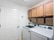 Bright laundry room boasts updated washer and dryer, and custom cabinet storage at 383 Harlow Ln, The Villages, FL 32163