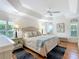 Bright main bedroom featuring tray ceiling, hardwood floors, and plantation shutters at 383 Harlow Ln, The Villages, FL 32163