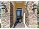 Close-up of front door with stone accents, elegant lighting, and a welcoming entrance mat at 4651 Sw 65Th Pl, Ocala, FL 34474