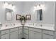 Bright bathroom featuring dual sinks, white cabinets, and elegant decor at 503 Verlander St, The Villages, FL 34762