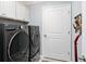Laundry room with front-loading washer and dryer set and ample storage cabinets at 503 Verlander St, The Villages, FL 34762