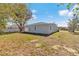 The back of the light gray stucco home and yard. Three white framed windows on the rear at 509 Marion Oaks Trail, Ocala, FL 34473