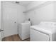A clean laundry room with a white washer and dryer, white walls, and wood-look floors at 509 Marion Oaks Trail, Ocala, FL 34473